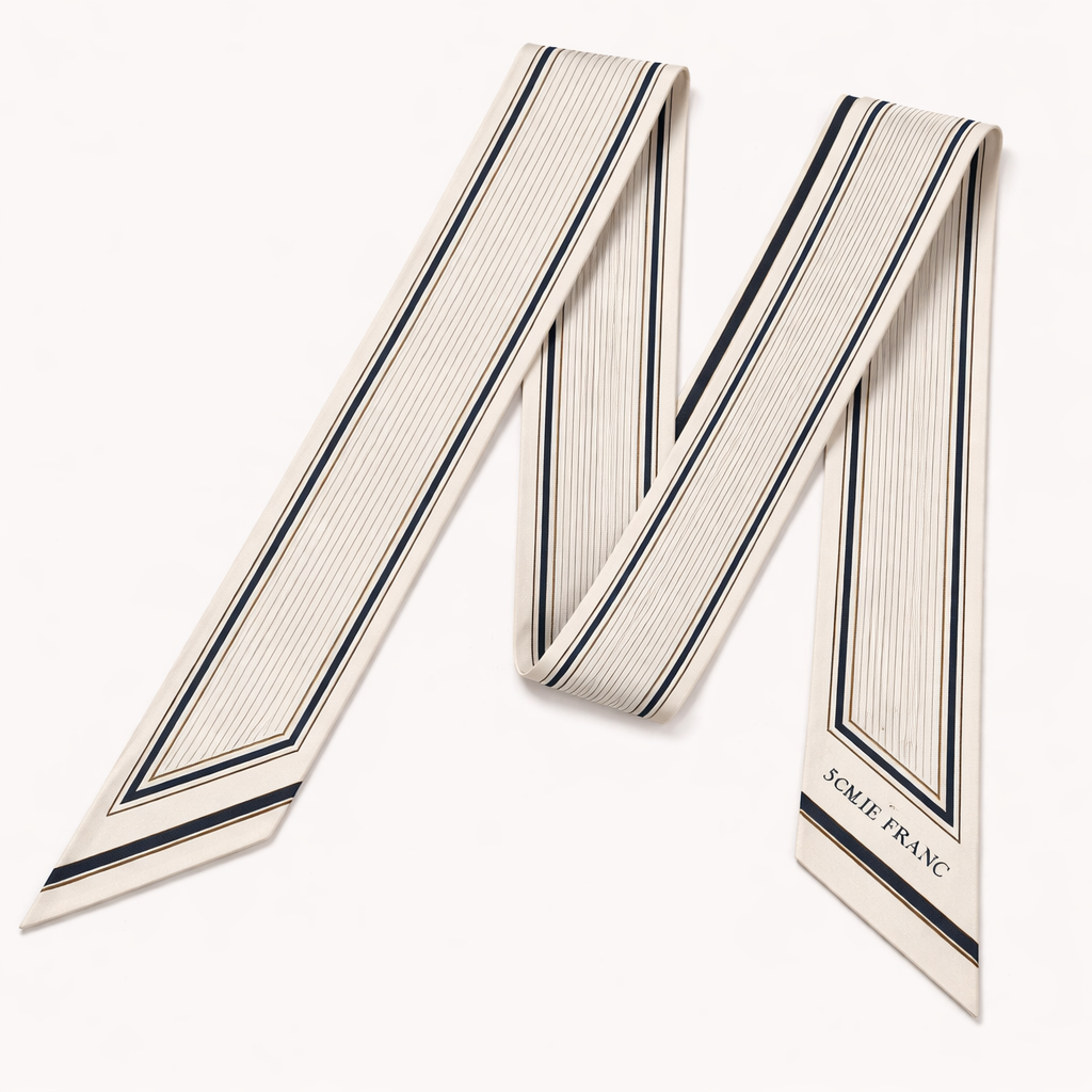 Design a 5cm x 86cm silk twill scarf for a luxury French brand called Jolie Franc. The design is classic, timeless, and tailored. Feature a precise double-line frame running the length of the scarf. Interior pattern should be architectural micro-stripes inspired by fine suiting. Color palette: ivory base with inky navy and muted antique gold accents. Hand-rolled edges. Minimal, structured, elegant, and instantly recognizable when wrapped around a Kelly-style bag handle or worn for evening.
Design a 5cm x 86cm silk twill scarf for a luxury French brand called Jolie Franc. The design is classic, timeless, and tailored. Feature a precise double-line frame running the length of the scarf. Interior pattern should be architectural micro-stripes inspired by fine suiting. Color palette: ivory base with inky navy and muted antique gold accents. Hand-rolled edges. Minimal, structured, elegant, and instantly recognizable when wrapped around a Kelly-style bag handle or worn for evening., classic style, show front and back