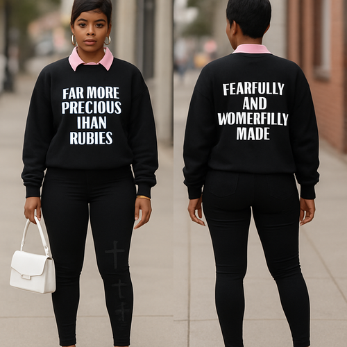 Black woman 
Pixie cut 
Pink collared shirt 
Black sweater shirt says far more precious than rubies in white 
On the back it says fearfully and wonderfully made in white 
Tight black pants with 3 black crosses on them 
Pink heels 
White purse 
Gold jewelry 


