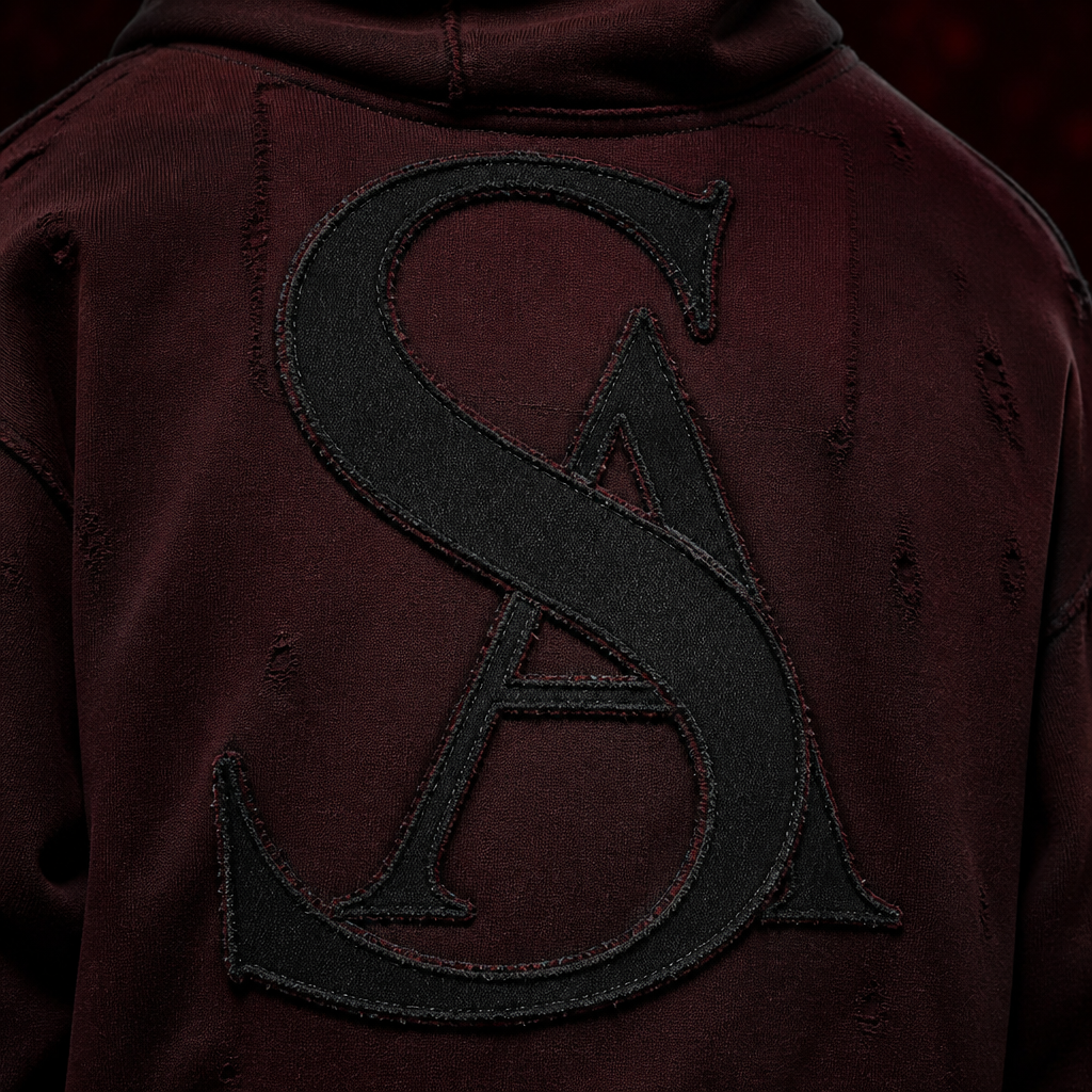 Close-up luxury product shot of the ASORAE ORIGIN hoodie.
Focus on the giant back logo.
Black distressed appliqué fabric layered over deep wine-red textile.
Extreme fabric detail.
Visible stitching.
Premium craftsmanship.
Luxury fashion campaign lighting.
Macro photography.
Ultra realistic.
Fashion-house quality.
Dark wine-red reflections.
Presence Without Noise.
Use the exact AS monogram shown in the reference image.
The monogram consists of a large elegant serif S placed in the foreground.
The A sits behind the S on the right side.
The S passes through the center of the A and remains the dominant visual element.
Both letters are fully recognizable while appearing as one unified luxury monogram.
Thin to medium stroke widths.
Fashion house typography.
Timeless luxury aesthetic.
Do not redesign the logo.
Do not create alternative letter shapes.
Keep the exact structure, proportions and relationship between the S and A from the reference image.
The AS monogram must appear exactly as shown in the reference image.
No reinterpretation.
No modernized version.
No alternative monogram.
No logo redesign.
Maintain identical positioning, overlap, proportions and elegance.
photorealistic fashion design, Close-up luxury product shot of the ASORAE ORIGIN hoodie.
Focus on the giant back logo.
Black distressed appliqué fabric layered over deep wine-red textile.
Extreme fabric detail.
Visible stitching.
Premium craftsmanship.
Luxury fashion campaign lighting.
Macro photography.
Ultra realistic.
Fashion-house quality.
Dark wine-red reflections.
Presence Without Noise.
Use the exact AS monogram shown in the reference image.
The monogram consists of a large elegant serif S placed in the foreground.
The A sits behind the S on the right side.
The S passes through the center of the A and remains the dominant visual element.
Both letters are fully recognizable while appearing as one unified luxury monogram.
Thin to medium stroke widths.
Fashion house typography.
Timeless luxury aesthetic.
Do not redesign the logo.
Do not create alternative letter shapes.
Keep the exact structure, proportions and relationship between the S and A from the reference image.
The AS monogram must appear exactly as shown in the reference image.
No reinterpretation.
No modernized version.
No alternative monogram.
No logo redesign.
Maintain identical positioning, overlap, proportions and elegance.
, just the design no text